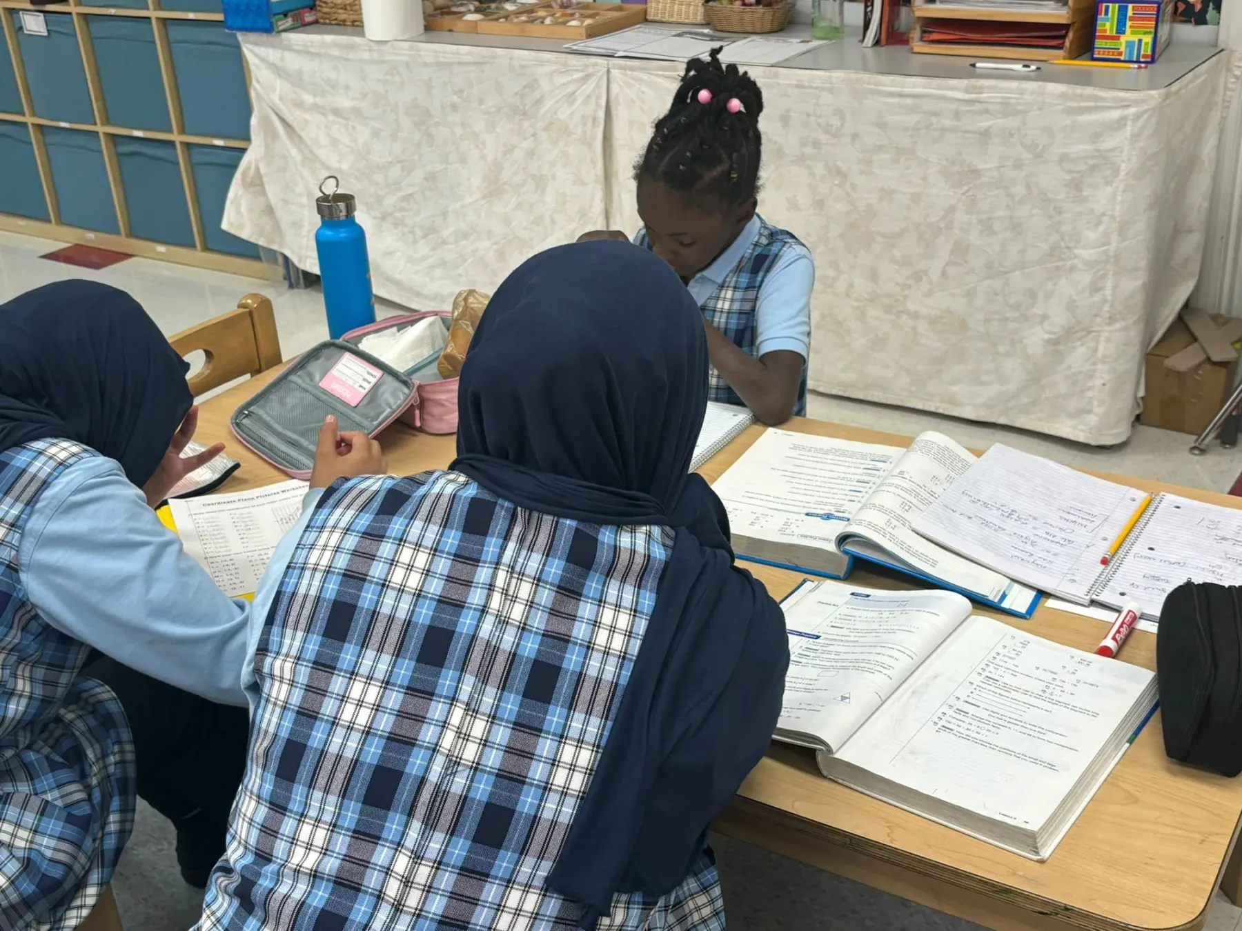 Children working through assignments together at a classroom table