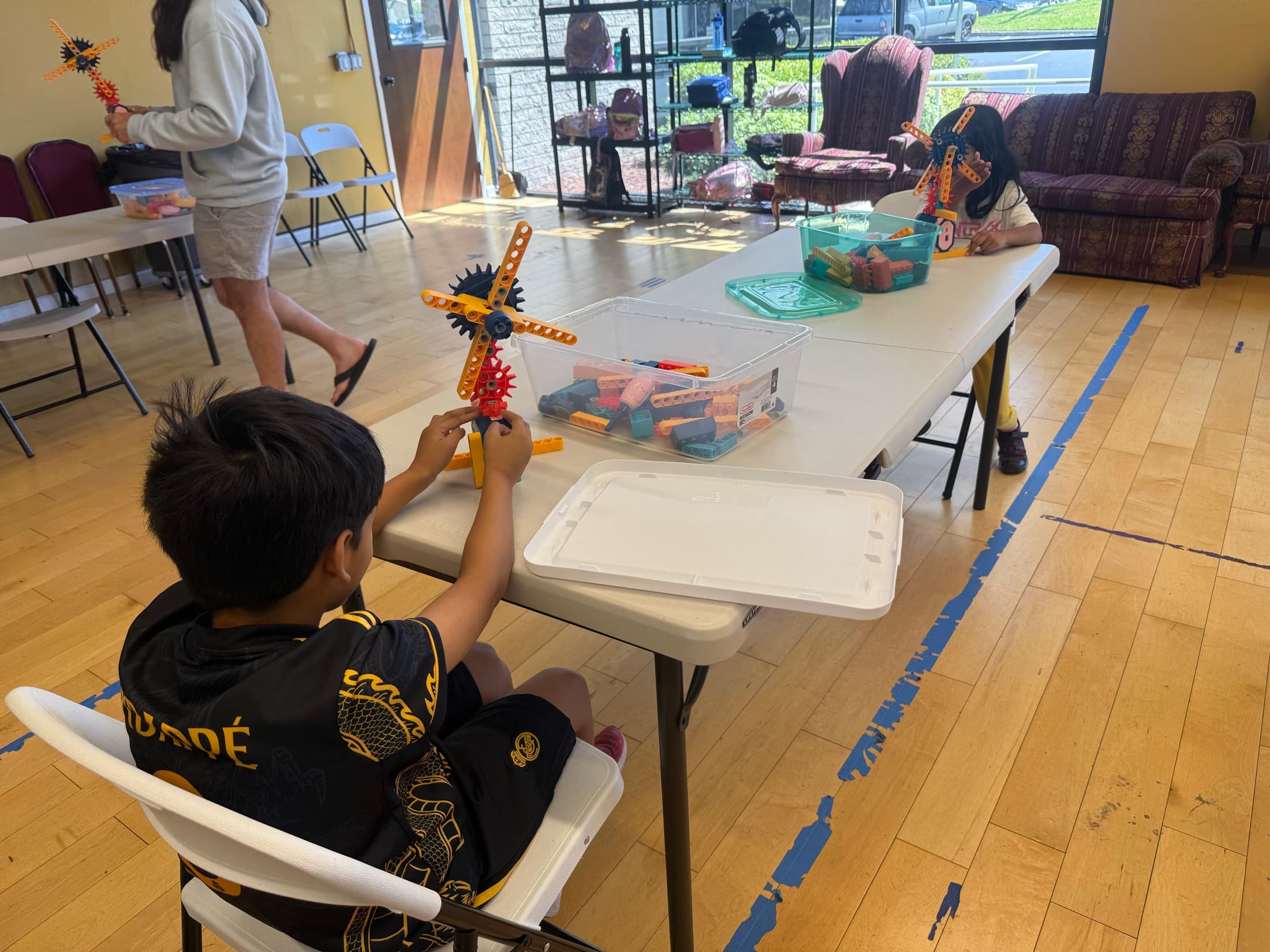 A child showing a colorful construction project at an activity table